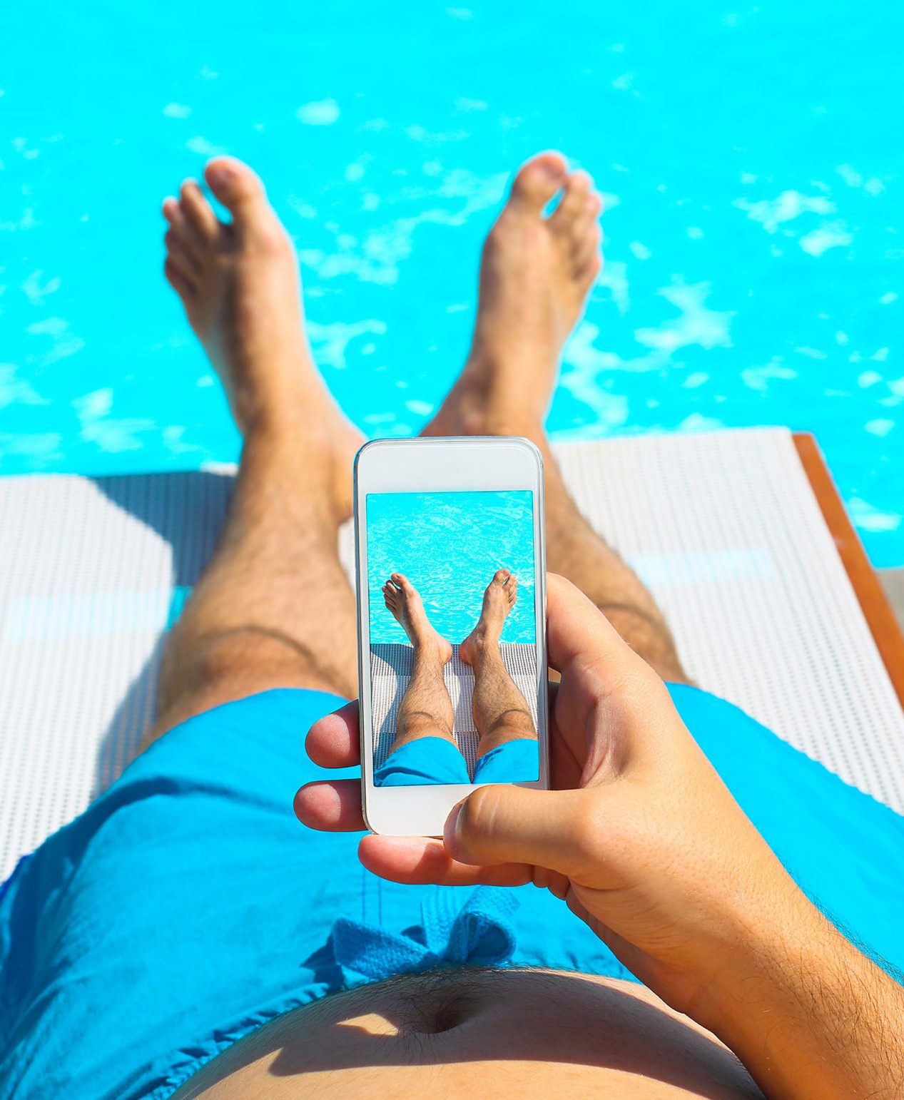 Young man lying on sunbed near pool with phone. Summer vacation