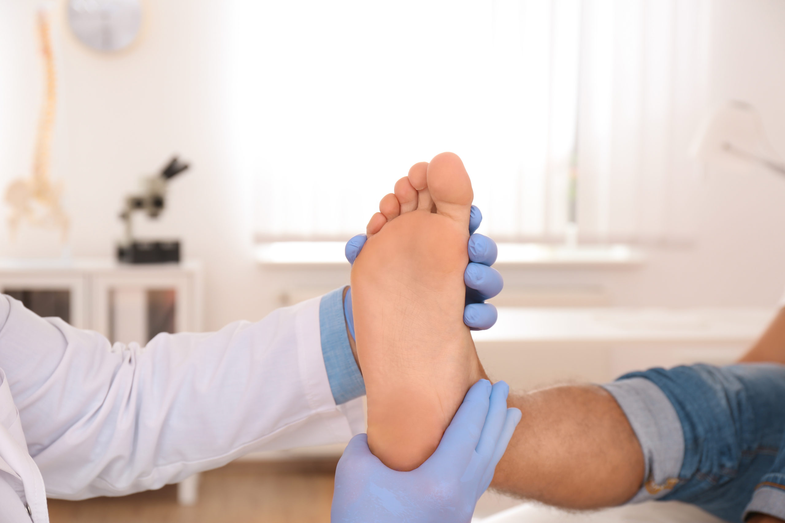 A man in the middle of bunion recovery has his foot examined by his surgeon.